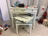 Front view of child's white vanity with three drawers stacked over matching upholstered stool. Vanity holds miscellaneous items not included.