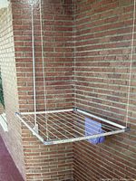 Image showing the white rectangular metal frame drying rack attached to ceiling, with one piece of cloth hanging on it and the pulley cord visible.