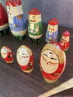 Close-up image showing four Christmas Santa Claus matryoshka dolls of different sizes with visible paint wear and aged surfaces.