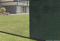 Green composite privacy screen attached to chain link fence showing material and binding details.
