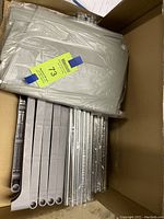 Unassembled parts including fabric shelves, plastic frame connectors, and metal rods in a box.