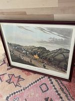 Full view of framed antique print on a patterned carpet showing rural landscape with horse carriage.