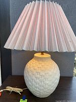 Full front view of the ceramic lamp base with pink pleated fabric shade.