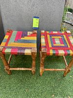 Pair of wooden stools with colorful woven seats, showing overall view and condition.