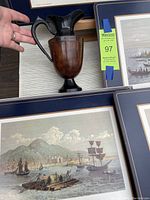 Close up of heavy metal pitcher with wood burl effect in front of three framed Montreal prints