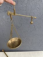 Side view of reproduction Roman market scale, showing brass basket suspended by chains and balance arm with counterweight