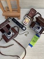 Photo showing Kodak Retinette Type 030 and Balda cameras with their leather cases, Vivitar 24mm camera, Zeiss Ikophot light meter, and auction tag