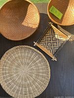 Top view of four woven wicker items including three circular wicker baskets of varying sizes and one small woven wall display with geometric pattern.
