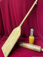Photo showing pop art wooden pepper mill, antique rolling pin, and wooden paddle on red background