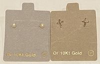 Two pairs of stud earrings displayed on cards labeled Or 10Kt Gold, one pair with pearls and one pair cross-shaped gold studs.