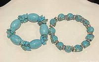 Two turquoise beaded stretch bracelets on a dark background showing overall design and bead arrangement.