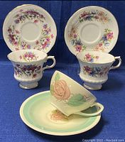 Two Paragon teacups with matching floral saucers and one Susie Cooper teacup with rose motif and coordinating saucer.