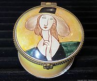 Top view of round copper trinket box with yellow enamel and Modigliani-style painted woman on lid.