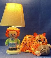 Front view of Raggedy-Anne lamp lit with Tiffany style cat lamp beside it, showing details of lampshade and cat lamp's intricate stained glass design