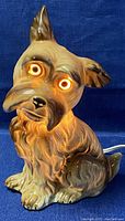 Front view of the ceramic dog lamp lit showing illuminated eyes