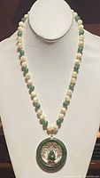 Front view of necklace on white display bust showing bead colors and pendant details