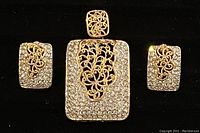 Front view of vintage FAC rectangular pendant and pair of matching earrings featuring gold-tone floral filigree and clear rhinestones.