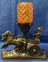 Front view of the vintage Roman chariot spelter lamp with textured orange glass shade, showing sculpture details and the lamp socket.