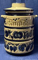 Front view of vintage ceramic rumtopf crock pot jar with embossed text and fruit decoration.