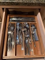 View into top drawer showing stainless steel knives, forks, spoons arranged in bamboo flatware organizer tray.