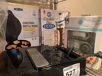 Lot overview showing Bella Christmas Waffle Maker, Wilton Cookie Pro Ultra cookie press, Disney Mickey Mouse waffle maker, and Martha Stewart thermometer box