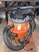 Photo of orange and black Ridgid blower vac with attached hoses and extension cord, showing overall device condition.