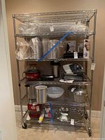 Front view of metal shelving rack fully loaded with various kitchen items and plastic wrap packages to show shelf design and capacity