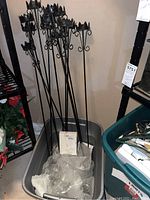 Wide view of multiple black wrought iron outdoor candleholders grouped together inside a bin