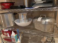 Photo showing vintage aluminum pressure canning pot (22QT) without lid, silver and gold ice bucket with tongs, white ceramic bowl, and Magnalite Classic roaster with lid on metal shelving.