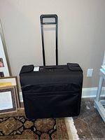 Front view of the black rolling garment suitcase with handle extended, showing the overall design and condition.