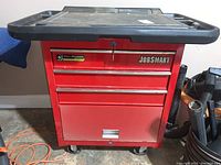 Front view of red JobSmart rolling tool chest with plastic top and casters, drawers closed, key inserted