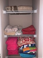 Full view of shelving with stacks of folded towels and bathmats in various colors and types.