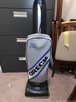 Full view of the Oreck XL Hypoallergenic vacuum, showing the gray fabric bag with blue trim and logo, wrapped power cord, base, and handle.