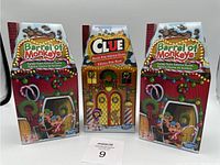 Three unopened boxed games: Clue North Pole Edition and two Barrel of Monkeys Candy Game editions, all with holiday-themed packaging.