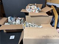 Four boxes containing glassware wrapped in newspaper, packed in cardboard boxes.