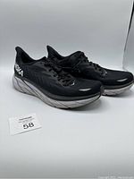 Pair of black Hoka Clifton 8 shoes angled view showing left and right shoes with visible wear on soles