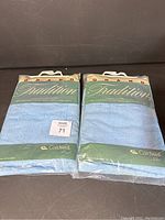 Two packages of Grand Tradition luxury bath sheets by Caldwell in sealed packaging, light blue color