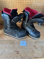 Pair of black and red K2 men's snowboard boots size 11, showing side view and overall exterior condition.