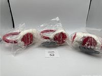 Three Tim Hortons earmuffs in clear plastic wrapping positioned side by side on white background.