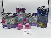 Lot of assorted toys including Littlest Pet Shop figures, Hatchimals Pixies dolls, LOL Surprise capsule, and Batman figure in packaging