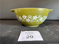 Front view of vintage olive green Pyrex mixing bowl with white flower pattern, showing one pouring spout