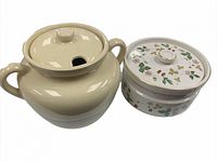 Two porcelain kitchenware items: a cream-colored McCoy jar with pastel stripes and a Wedgewood floral covered dish with gold accents.