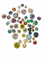 Photo showing a collection of assorted vintage buttons in various colors and sizes, featuring slogans and graphics.
