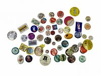 Photo shows 44 assorted vintage pinback buttons in various colors, shapes, and designs, spread out on a white background.