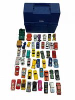Top down image showing 45 assorted vintage diecast Dinky cars arranged in rows below a vintage blue Thermos lunch pale.