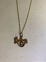 Close-up of the yellow gold 'Mother' pendant with cursive script and attached to the chain