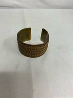 Front view of copper and brass adjustable bangle bracelet, showing braided wire design and open ends for resizing.