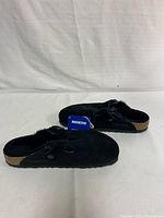 Side view of the pair of black Birkenstock Boston shearling clogs showing suede material and cork midsole.