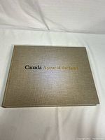 Top view of the closed book showing gray textured cover with title in black and gold letters.