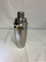 Front view of the shiny stainless steel cocktail shaker showing the full height and smooth polished finish.